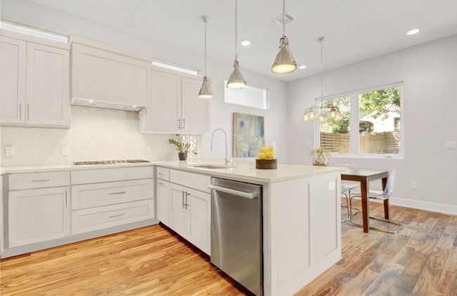 Kitchen featuring stovetop, visible vents, dishwasher, a sink, and a peninsula | Image 7
