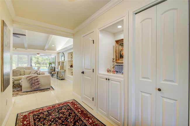The formal entryway opens to an elegant, light-filled family room with an open-concept design and serene golf course views. | Image 5