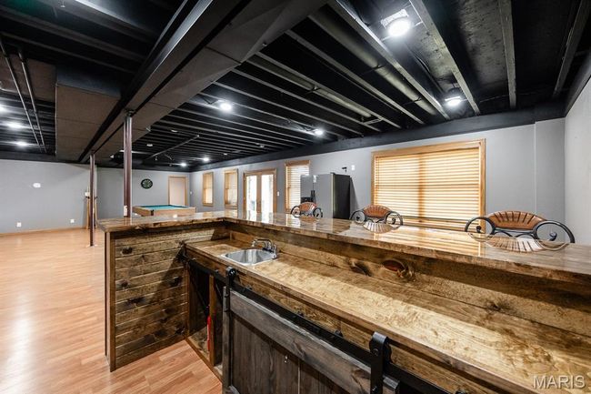 Kitchen with light wood-style flooring, a sink, and stainless steel fridge with ice dispenser | Image 34