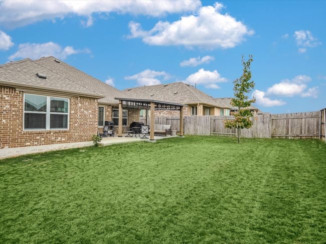 A backyard big enough for a game of kickball with the littles or ball tossing for the pup! This home has a full yard sprinkler system. Here you can see the Pergola and extensions for the 2 posts to give uninterrupted patio space. The house is fully guttered, so as not to interrupt a good visit during a light spring shower while enjoying the backyard. | Image 19