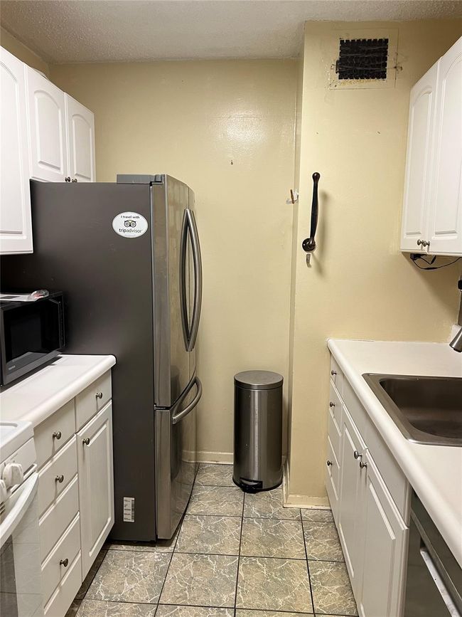 Kitchen featuring dishwashing machine, range, a sink, white cabinetry, and light countertops | Image 8