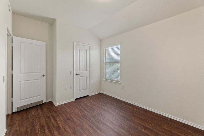 Unfurnished bedroom with dark wood-style floors and lofted ceiling | Image 14