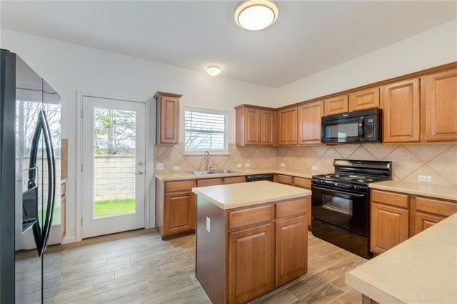 Kitchen featuring black appliances, a sink, light countertops, and a kitchen island | Image 8