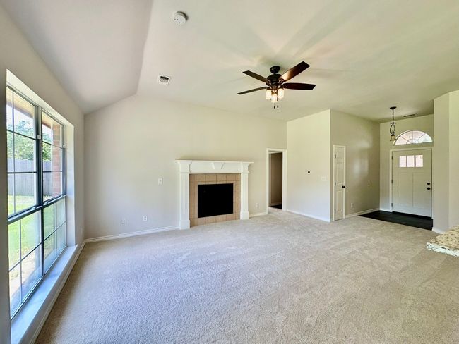 Unfurnished living room featuring carpet, ceiling fan, a tile fireplace, and vaulted ceiling | Image 22