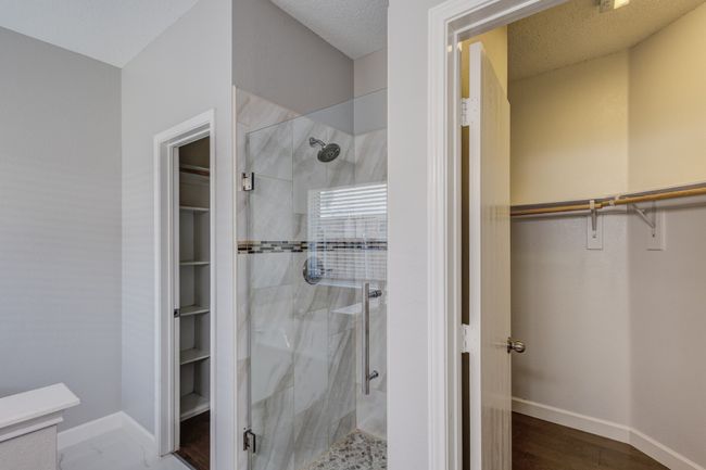 Bathroom featuring a spacious closet, a shower stall, and baseboards | Image 28