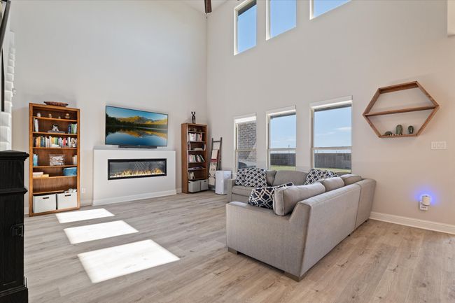 Living room featuring wood finished floors, a towering ceiling, a glass covered fireplace, and baseboards | Image 14