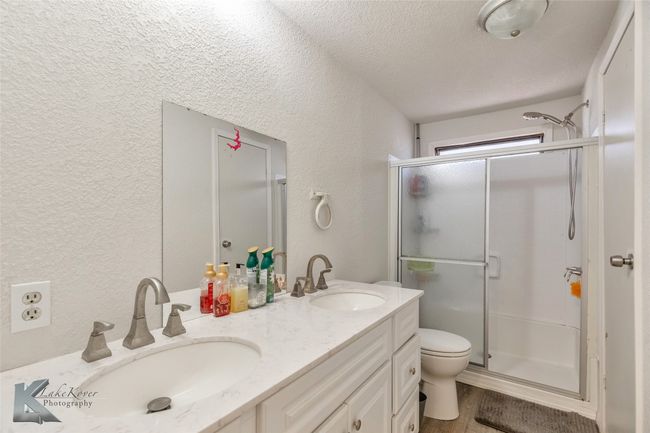Bathroom featuring a shower stall, a textured wall, and a sink | Image 17