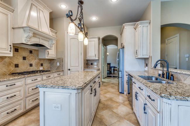 Kitchen with backsplash, custom range hood, arched walkways, stainless steel appliances, and a sink | Image 15