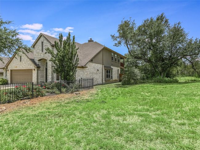 A designed green space flanks the entire right side of your home constructed of mostly stone and some stucco siding. | Image 30