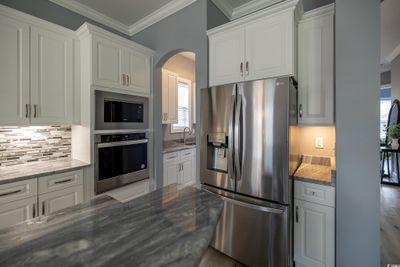 Kitchen with a wealth of natural light, white cabinetry, and stainless steel appliances | Image 3