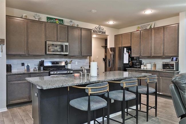 The kitchen boasts a beautiful open-concept design with ample cabinet space and a spacious island that doubles as a convenient breakfast bar. | Image 7