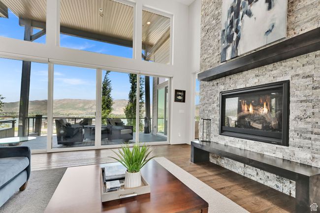 Living room featuring wood finished floors, plenty of natural light, a stone fireplace, a mountain view, and a high ceiling | Image 18