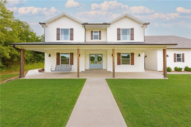 Modern farmhouse featuring concrete driveway, a porch, a front lawn, and metal roof | Image 6