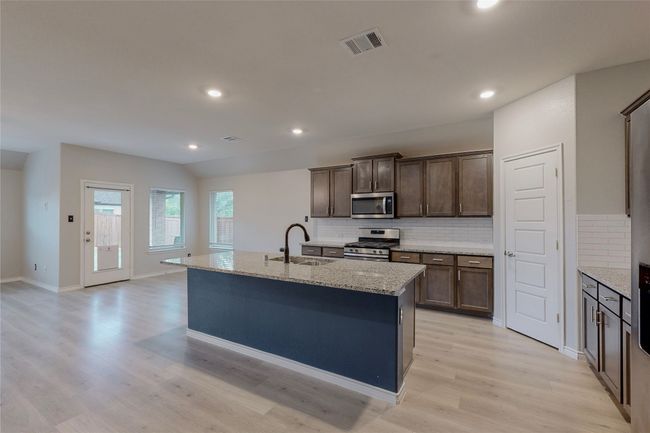 Kitchen featuring appliances with stainless steel finishes, light wood-type flooring, backsplash, a sink, and visible vents | Image 17