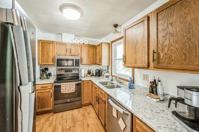 This kitchen features beautiful granite countertops, rich wood cabinets, and sleek stainless steel appliances, combining style and functionality | Image 2