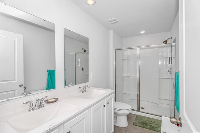Bathroom featuring vanity, toilet, an enclosed shower, and tile patterned flooring | Image 12