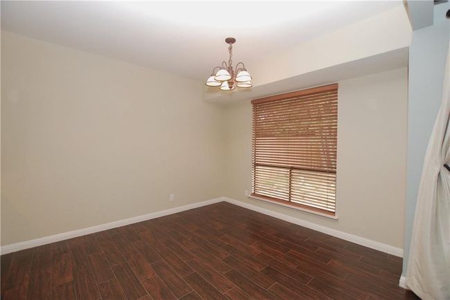 Empty room with a chandelier and wood-like tile floors | Image 10