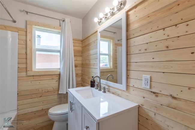 Bathroom with toilet, vanity, wood walls, and walk in shower | Image 7