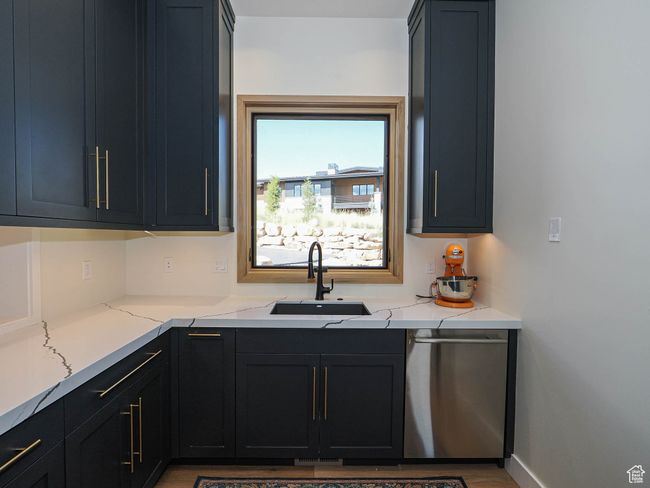 Kitchen featuring dishwasher, light stone counters, dark cabinetry, and wood finished floors | Image 40