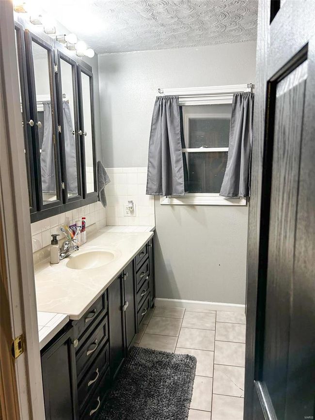 Bathroom featuring tile patterned floors, vanity, backsplash, and a textured ceiling | Image 16