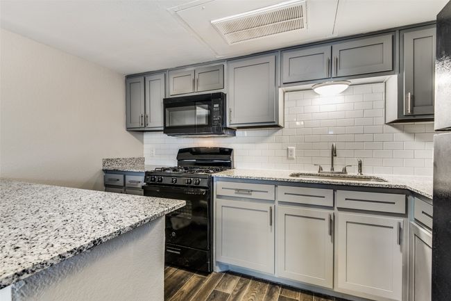 Kitchen with black appliances, gray cabinets, dark wood-type flooring, and a sink | Image 6