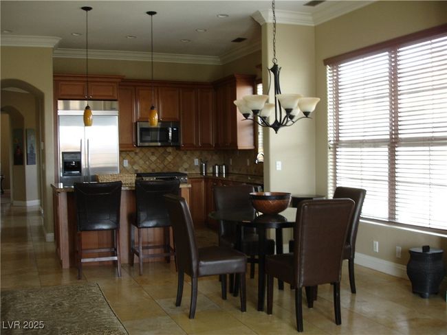 Dining room featuring arched walkways, a chandelier, baseboards, crown molding, and light tile patterned flooring | Image 4