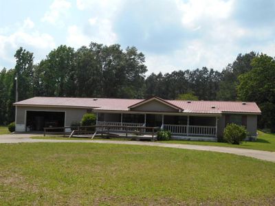 Ranch-style home featuring a front yard and a garage | Image 1