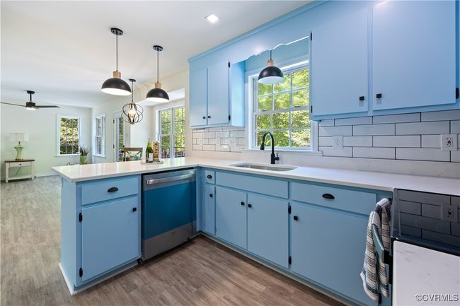 Kitchen featuring blue cabinets, a peninsula, a sink, dishwashing machine, and light countertops | Image 17