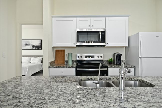 Kitchen with white cabinets, stone counters, appliances with stainless steel finishes, and a sink | Image 17