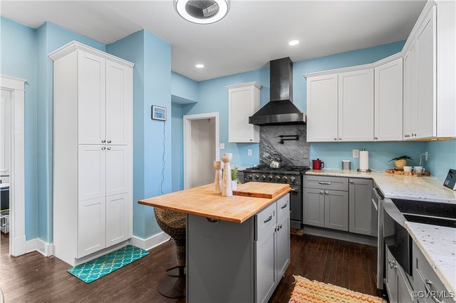 Kitchen featuring wall chimney exhaust hood, stainless steel appliances, dark wood-style floors, butcher block countertops, and gray cabinets | Image 14