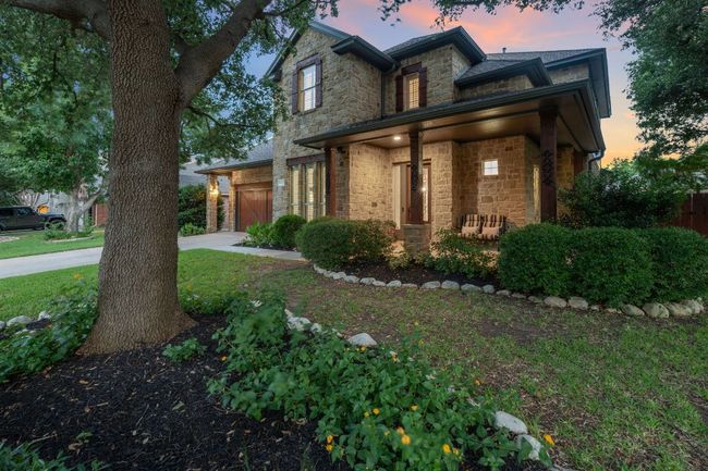 View of front of house with stone siding, concrete driveway, covered porch, an attached garage, and a yard | Image 25