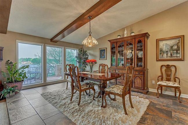 The wood beams carry through into the dining room, tying the spaces together with a warm, cohesive look.Three oversized windows offer picturesque views of the lake. | Image 12