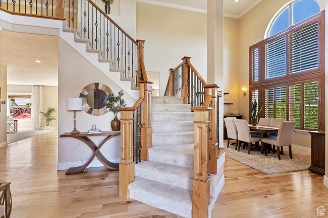 Staircase featuring crown molding, baseboards, wood finished floors, and a towering ceiling | Image 5