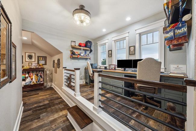 The custom stair railing seamlessly matches the balcony design and the railing on the private office space, creating a cohesive flow throughout the home. The upstairs office boasts two built-in desk areas, w/three windows that offer a bright view of the front of the home. The highlight of the space is the unique river table desktop, a one-of-a-kind feature that adds a touch of artistry to the office. Custom-built filing cabinet drawers provide ample storage, making this home office both stylish & functional | Image 30
