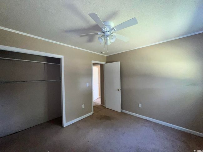 Unfurnished bedroom featuring ornamental molding, carpet, a closet, baseboards, and a textured ceiling | Image 10