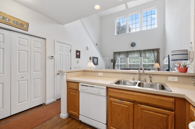 Kitchen with white dishwasher, a sink, wood finished floors, and light countertops | Image 15