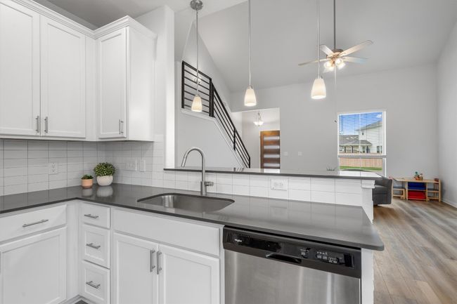 Kitchen with stainless steel dishwasher, a sink, dark countertops, tasteful backsplash, and ceiling fan | Image 11