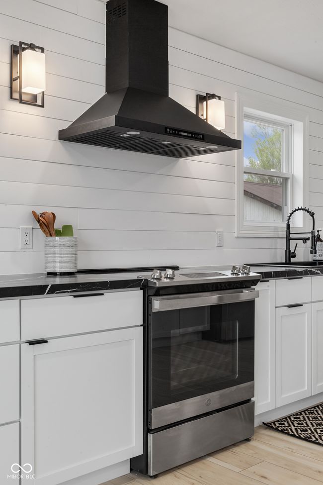 kitchen featuring white cabinetry, electric range, dark countertops, range hood, and a sink | Image 31