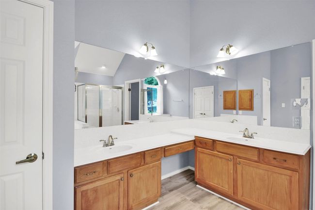 Master bathroom with a stall shower, double vanity, lofted ceiling, and vinyl plank floors | Image 31