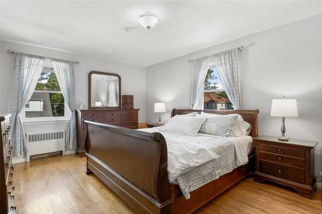Bedroom featuring radiator heating unit, multiple windows, light wood floors, and baseboards | Image 11