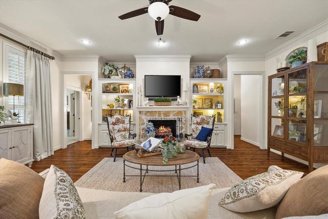 Living room featuring ceiling fan, crown molding, a stone fireplace, and dark hardwood / wood-style floors | Image 17