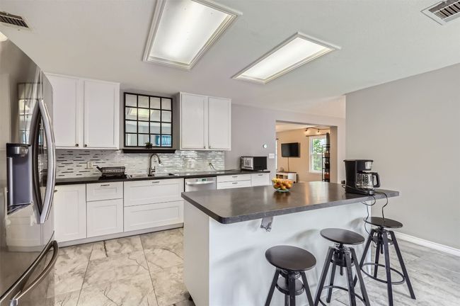 Kitchen with appliances with stainless steel finishes, dark countertops, a sink, and a kitchen breakfast bar | Image 11