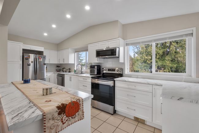 Kitchen featuring backsplash, visible vents, stainless steel appliances, and a sink | Image 4