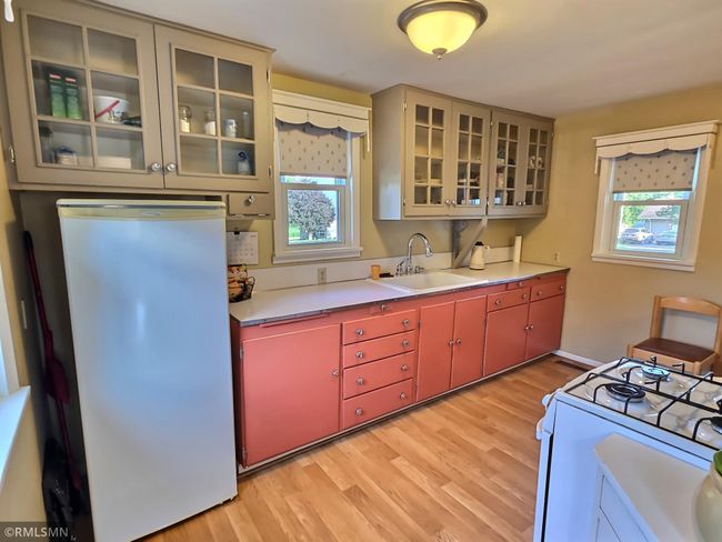 The kitchen is located on the backside of the home and offers wonderful views of the scenic backyard. The fun color combination of the lower cabinets ties in well with the glass uppers. | Image 6
