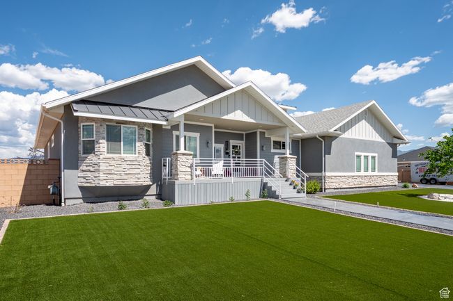 Craftsman-style home with stone siding, covered porch, a front lawn, and a standing seam roof | Image 10
