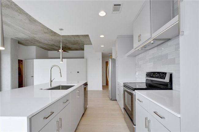 Kitchen featuring visible vents, light countertops, a sink, and stainless steel appliances | Image 6
