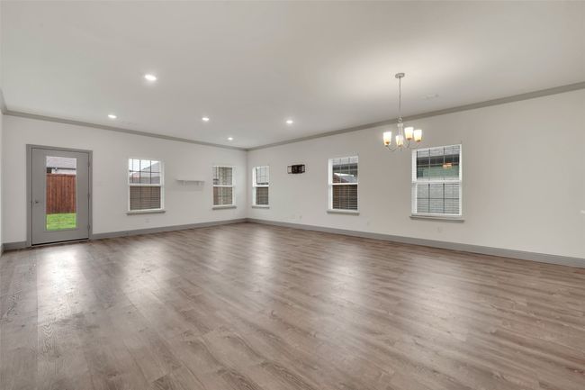 Unfurnished living room with ornamental molding, baseboards, a chandelier, and wood finished floors | Image 8