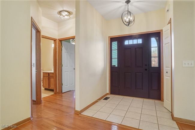 Entryway with baseboards, a chandelier, visible vents, and light wood-style floors | Image 15