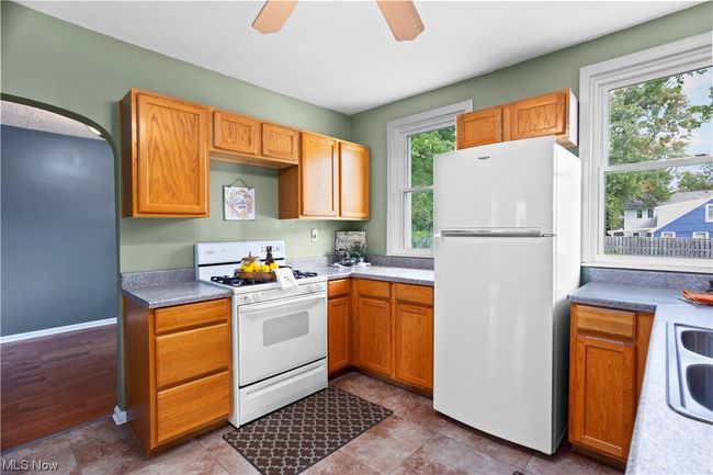 Kitchen with tile floors, brown cabinets, white appliances, and ceiling fan | Image 7
