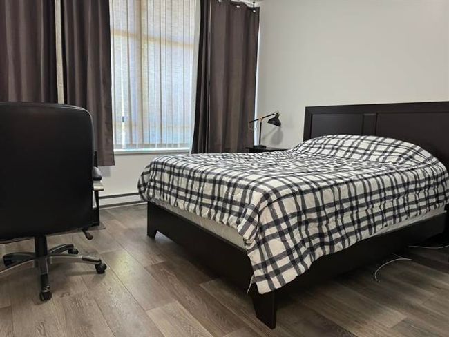 Bedroom with a baseboard heating unit and wood finished floors | Image 4